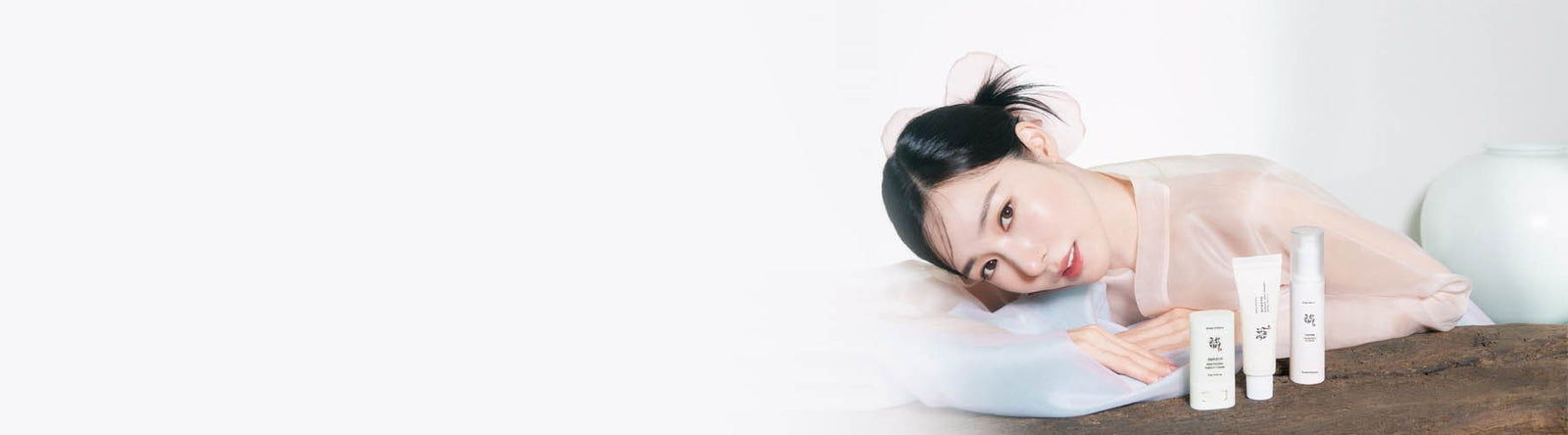 Beauty Of Joseon Brand Photo showing a Korean woman wearing a traditional costume lying in front of Beauty Of Joseon products