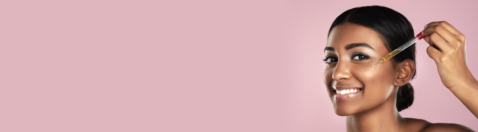 Jeune femme souriante d'origine d'Afrique noire mettant quelques gouttes de sérum sur le visage