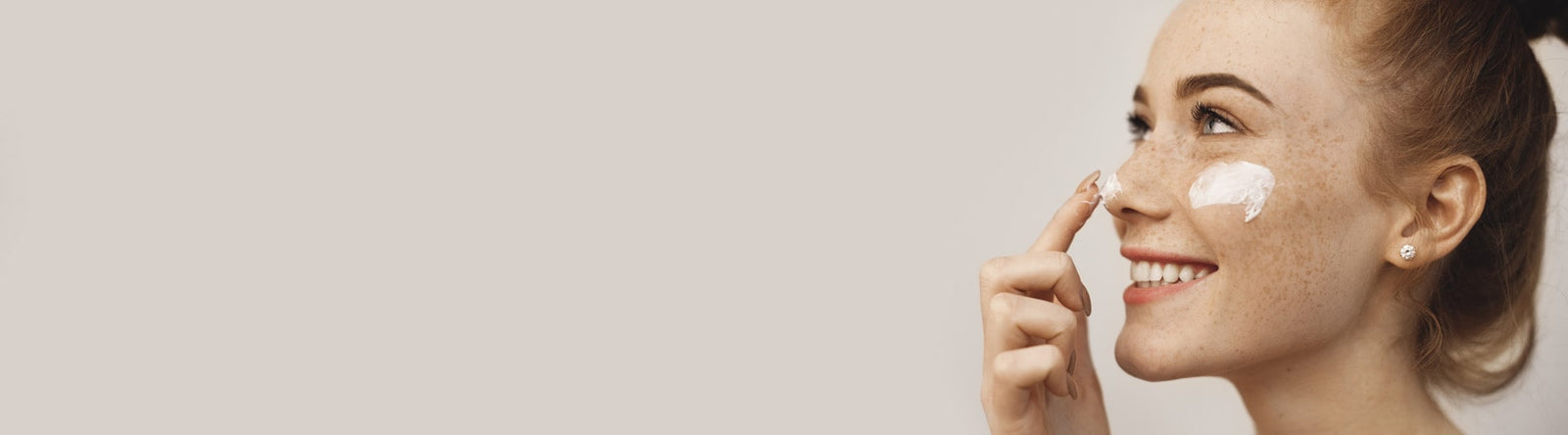 Jeune femme souriante jouant avec une émulsion hydratante sur son nez