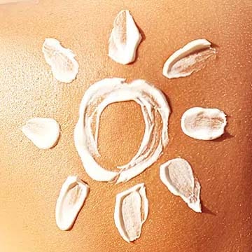 Soleil dessiné avec de la crème solaire sur une peau bronzée