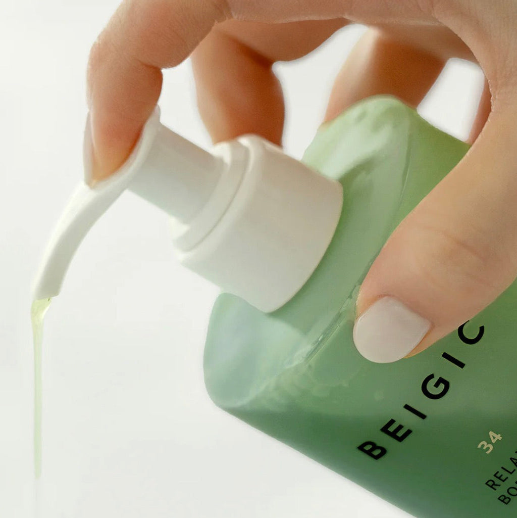 Zoom sur la texture gel-huile ambrée et fluide du nettoyant corps BEIGIC, révélant une formule riche qui fond sur la peau pour se transformer en mousse soyeuse.