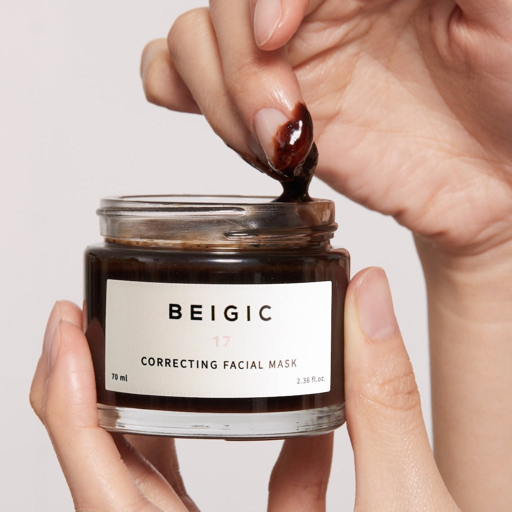 Le pot de masque BEIGIC ouvert à côté d'une cuillère en bois et de grains de café, baigné dans une atmosphère de spa lumineuse et relaxante.