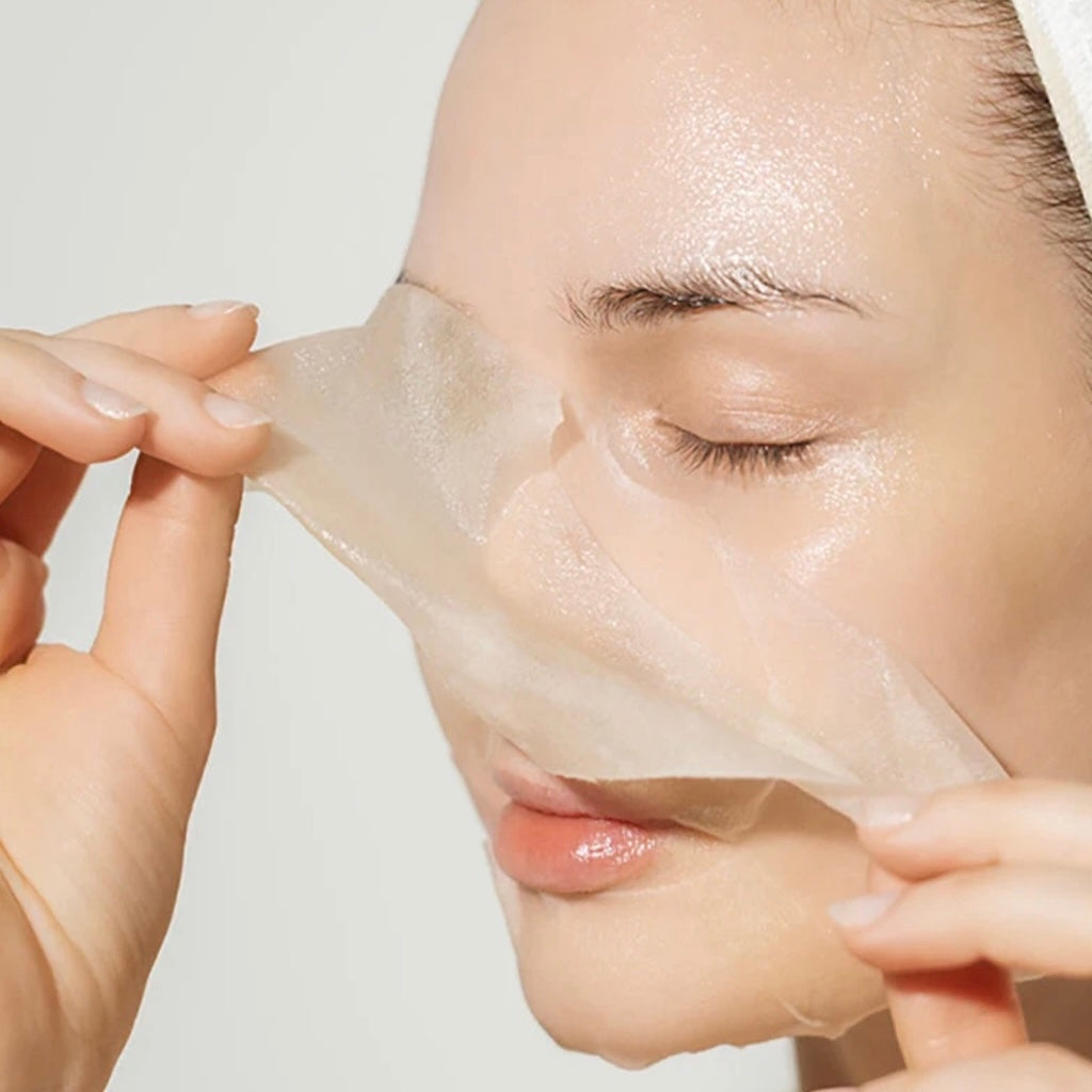 Gros plan sur la texture d'un des masques en fibres de bambou gorgé de son essence riche, prêt à libérer ses actifs sur la peau.