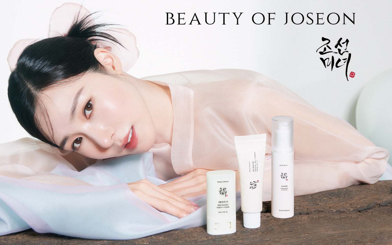 Mannequin de la marque Beauty of Joseon avec une belle peau portant des vêtements traditionnels devant les produits de soins de la peau de Beauty of Joseon