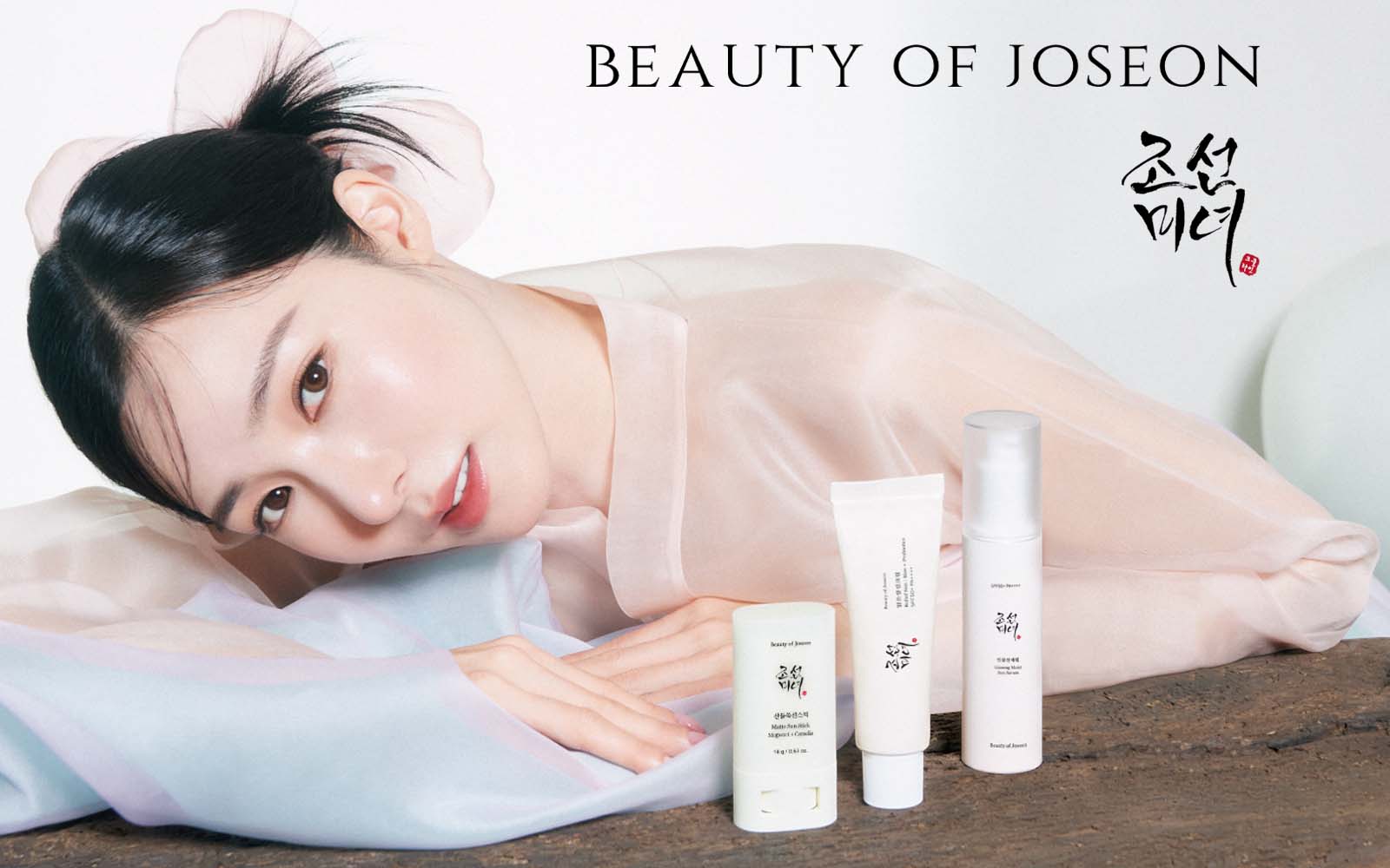 Beauty of Joseon Brand model with beautiful skin wearing traditional clothe in front of skincare products from Beauty of Joseon