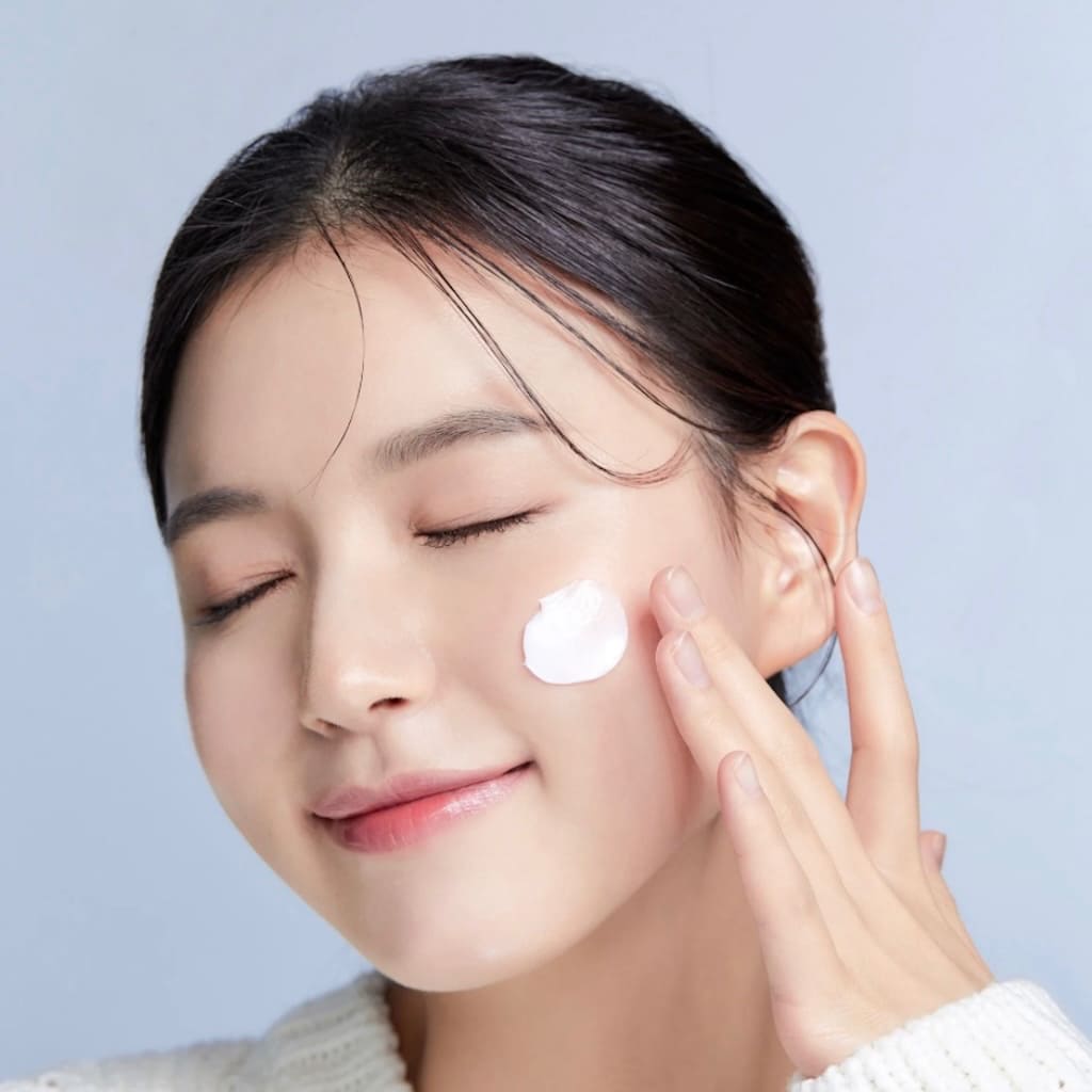 Application de la crème Ma:nyo Panthetoin sur le visage pour apaiser les tiraillements.