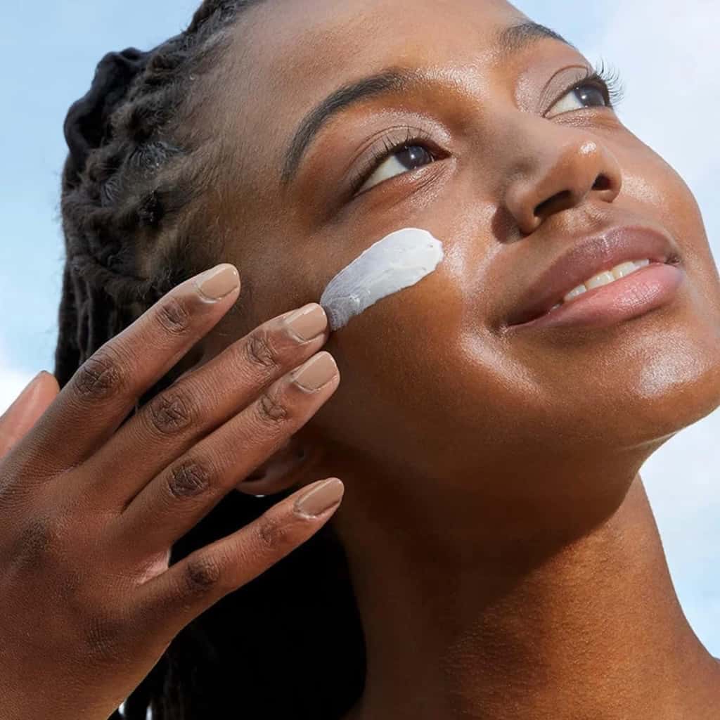 Application de la crème solaire COSRX sur le visage pour un fini semi-mat sans traces blanches.