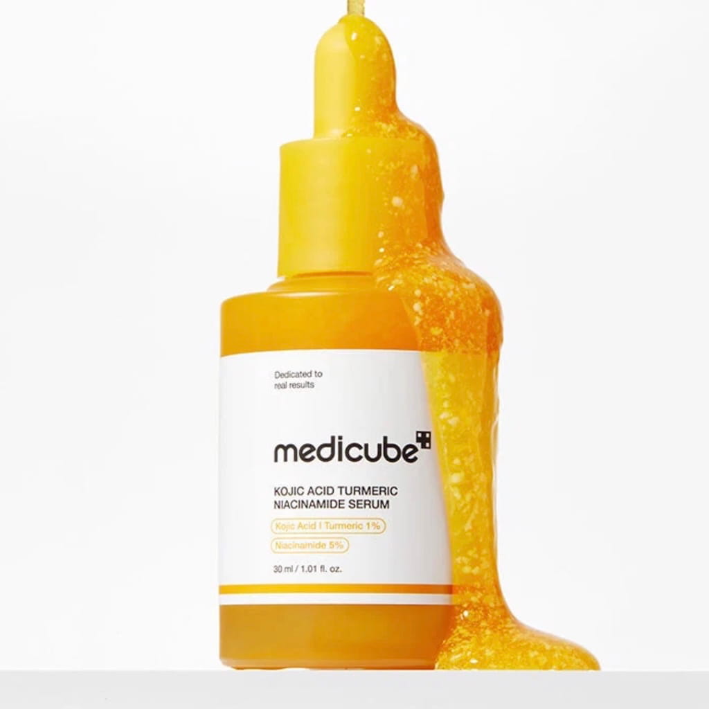 Application du sérum MEDICUBE sur le visage pour unifier le teint et réduire les taches.