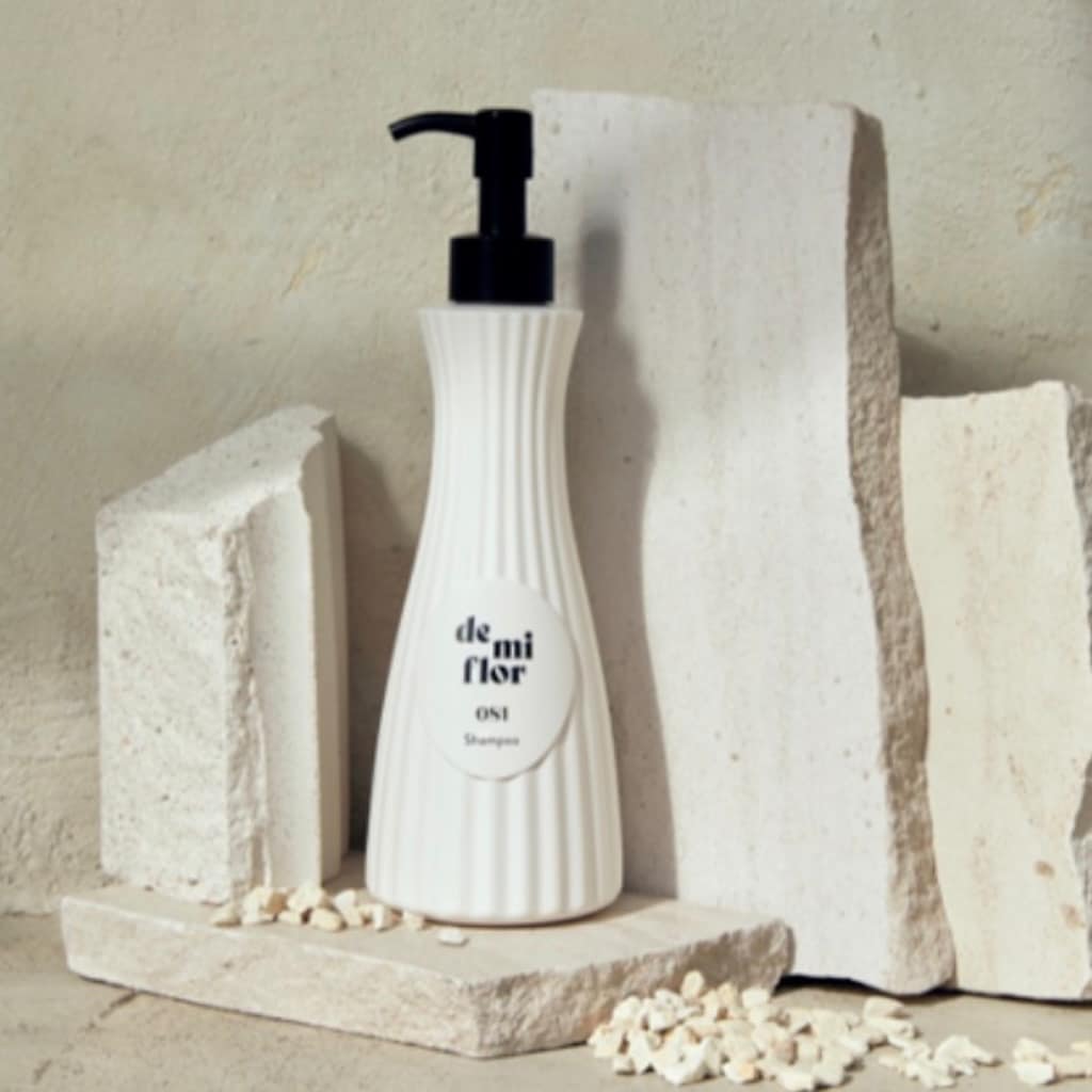 Flacon DE MI FLOR Shampoo Fleurage posé élégamment au bord d'une baignoire.
