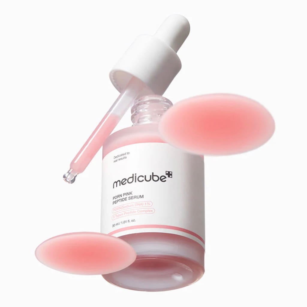 Texture fluide rose iconique du sérum Medicube PDRN prélevée à la pipette.