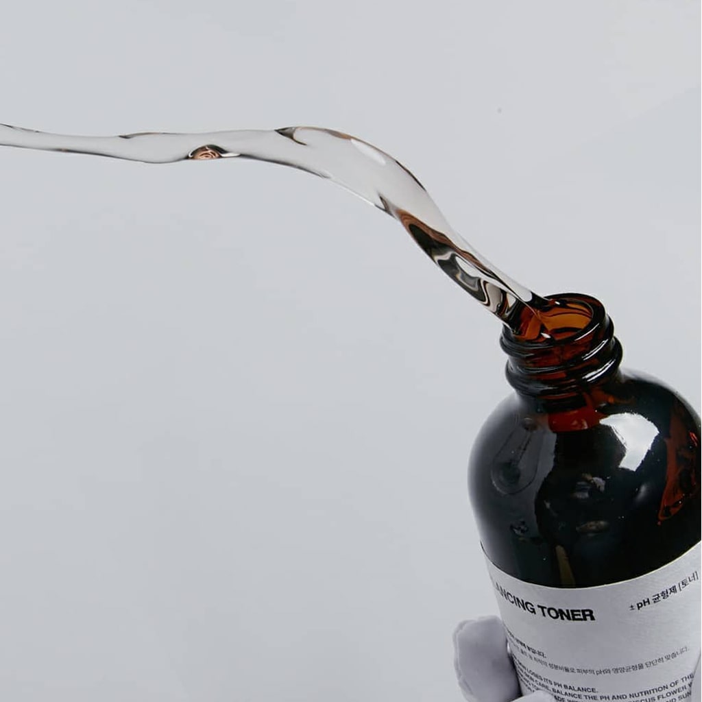 La lotion tonique équilibrante pH TOUN28, dans un flacon brun au bouchon argenté de 250 ml, met en valeur son utilisation et ses ingrédients, comme l'eau florale d'hibiscus. Un code-barres et l'étiquette « VEGAN » soulignent sa promesse de soins alliant nature et science.