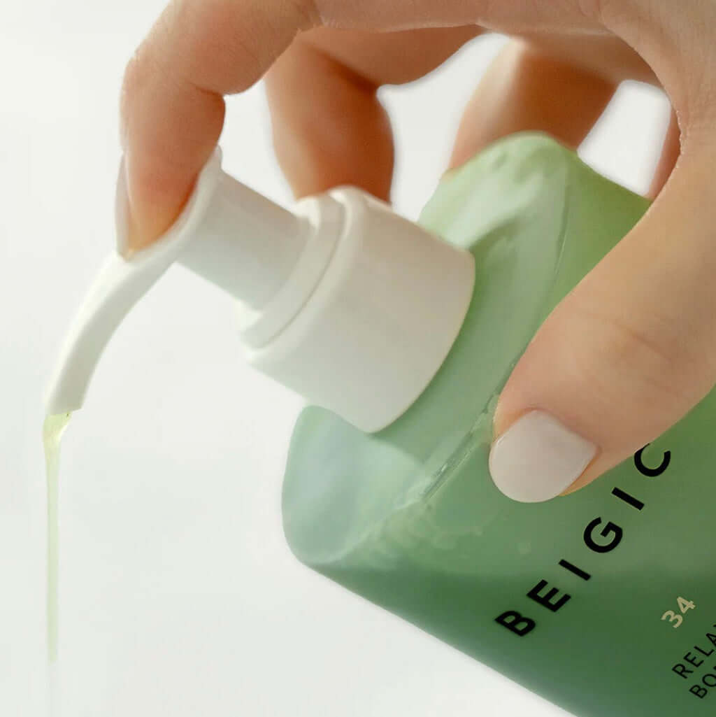 Zoom sur la texture gel-huile ambrée et fluide du nettoyant corps BEIGIC, révélant une formule riche qui fond sur la peau pour se transformer en mousse soyeuse.