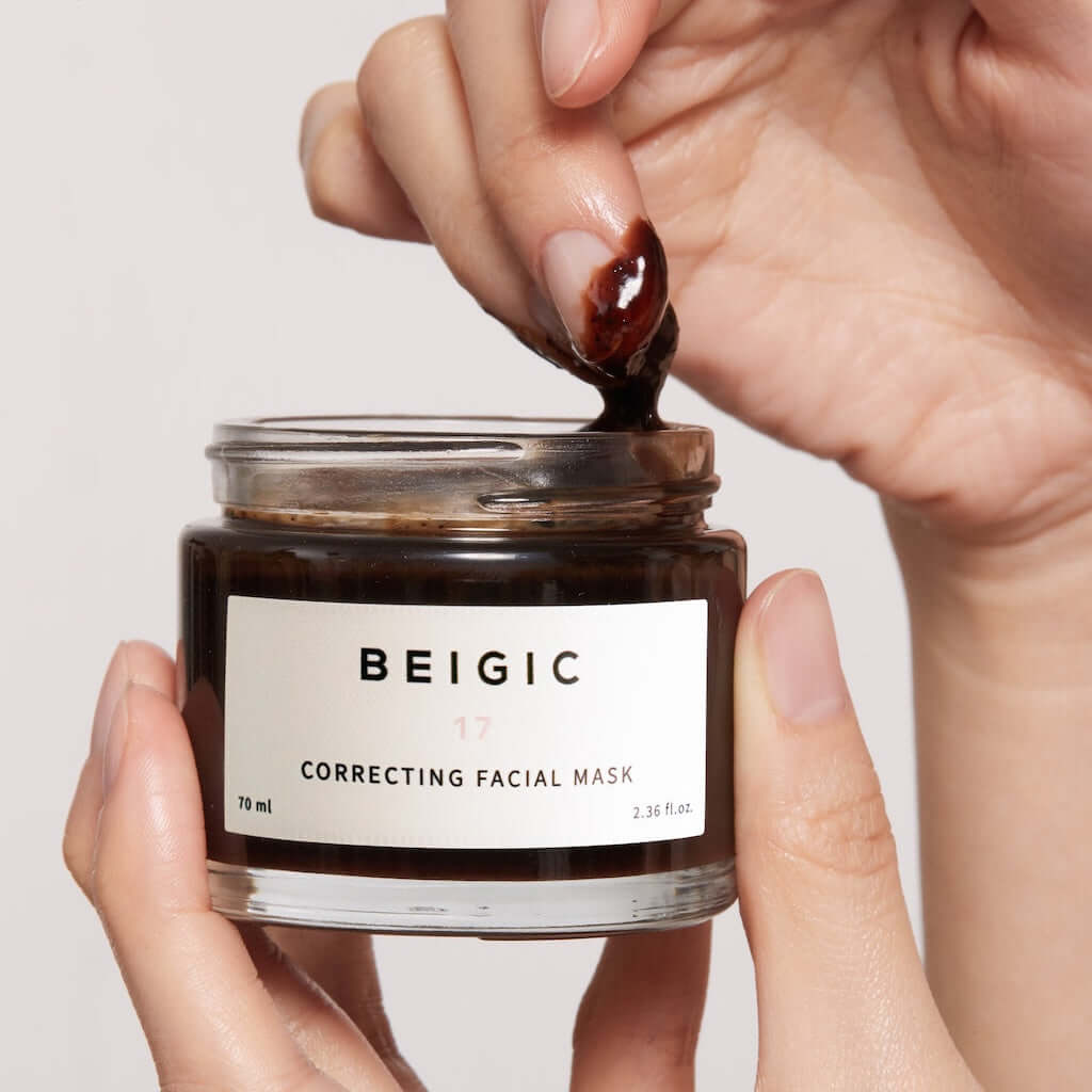 Le pot de masque BEIGIC ouvert à côté d'une cuillère en bois et de grains de café, baigné dans une atmosphère de spa lumineuse et relaxante.