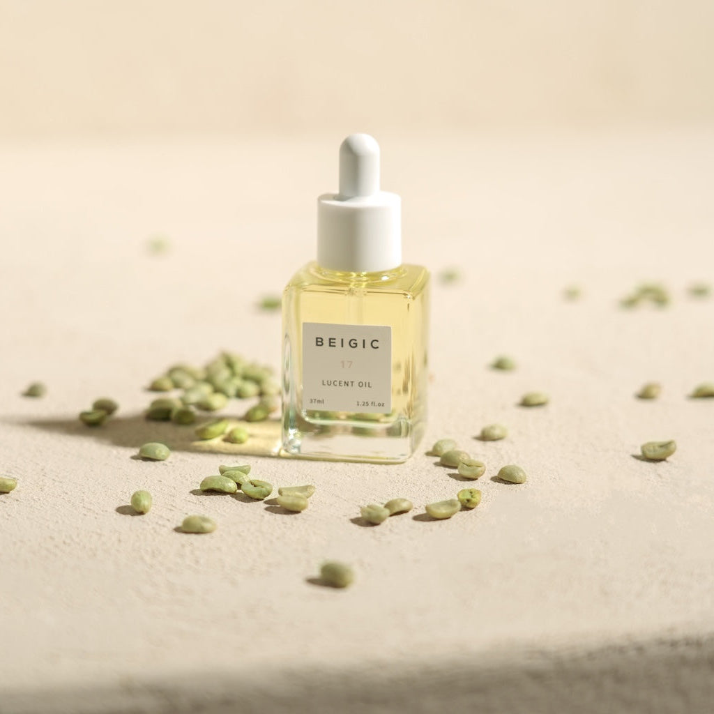 Le flacon d'huile BEIGIC capturant la lumière naturelle sur un comptoir de marbre, symbolisant la pureté, la clarté et le soin premium.
