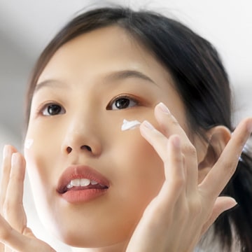 Jeune femme coréenne appliquant sur son visage un soin crème