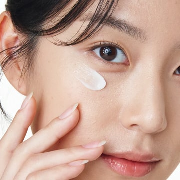 Jeune femme coréenne appliquant une crème contour des yeux